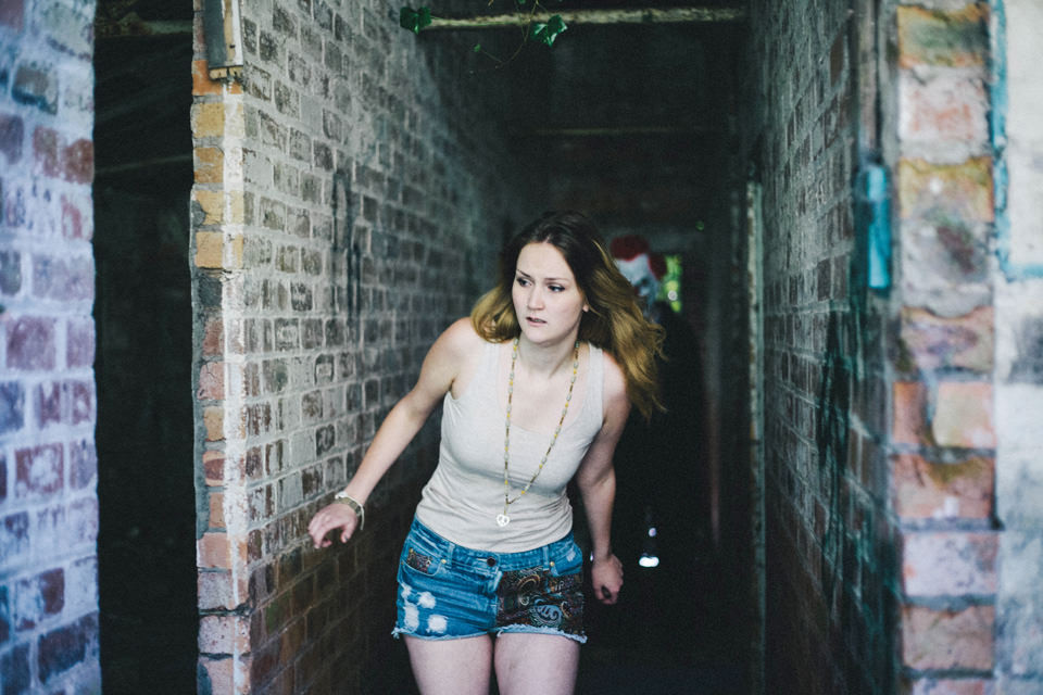 Girl running away from clown in abandoned building